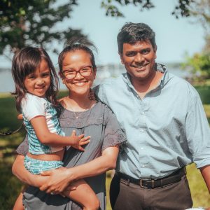 Smiling family enjoying time together outdoors in a sunny summer setting.